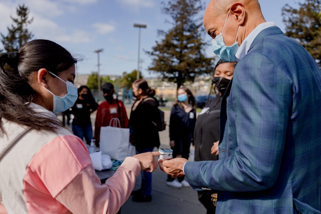 man in suit showing high school girl how to use an oxygen reader