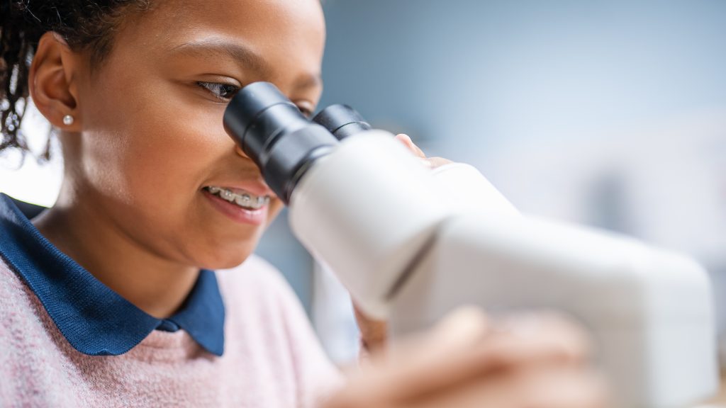 young black girl looking into a microscope